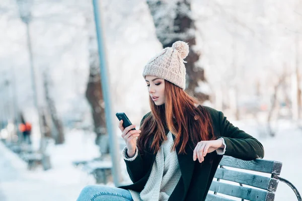 Fiatal nő, mosolygós, szúró telefon és a téli táj . — Stock Fotó