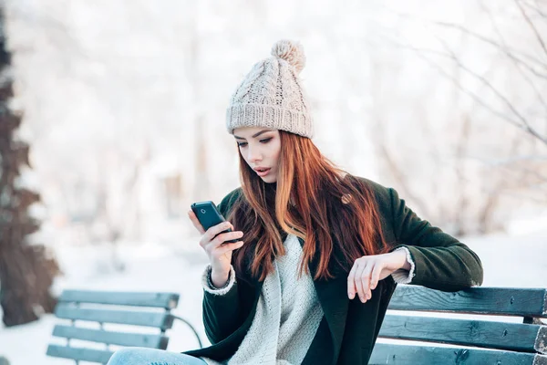 Fiatal nő, mosolygós, szúró telefon és a téli táj . — Stock Fotó