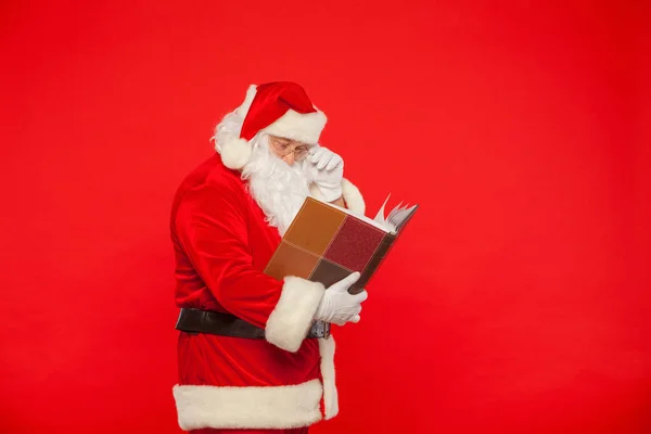 Санта-Клауса читає старі книги, на червоному тлі. Різдво — стокове фото