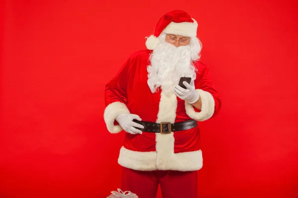 Foto de Santa Claus usando teléfono móvil, sobre un fondo rojo. Ch —  Fotos de Stock