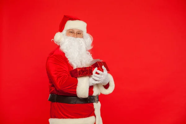 Photo of Santa Claus gloved hands holding red giftbox — Stock Photo, Image