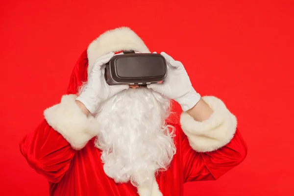 Père Noël portant des lunettes de réalité virtuelle, sur un fond rouge — Photo
