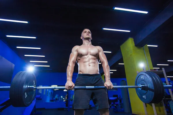 Entrenamiento muscular con barra de pesas en el gimnasio. Brutal culturista atlético hombre con abdominales perfectos, hombros, bíceps, tríceps y pecho. Entrenamiento de barras de elevación muertos —  Fotos de Stock