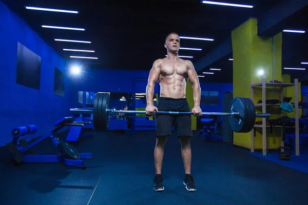 Svalnatý muž cvičení s činka v posilovně. Brutální kulturista atletický muž s perfektní abs, ramena, biceps, triceps a hrudníku. Mrtvý tah činky cvičení — Stock fotografie