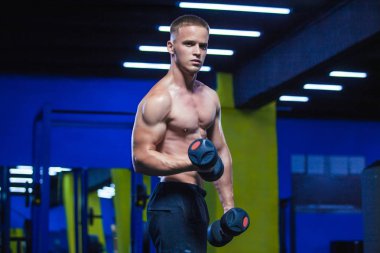 Güçlü bir adam dumbbells ile yapıyor. Spor salonunda sportif kaslı erkek fotoğrafı. Güç ve motivasyon