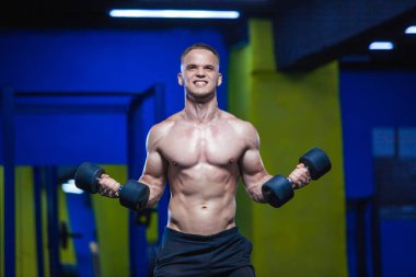 Güçlü bir adam dumbbells ile yapıyor. Spor salonunda sportif kaslı erkek fotoğrafı. Güç ve motivasyon
