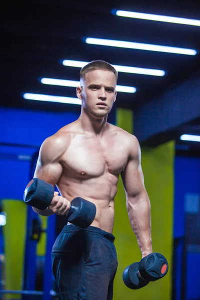 Un hombre poderoso haciendo ejercicios con pesas. Foto de hombre musculoso deportivo en el gimnasio. Fuerza y motivación —  Fotos de Stock
