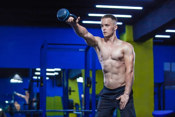 Portrét mladého muže svalnatý zvedání kettlebell v tělocvičně — Stock fotografie