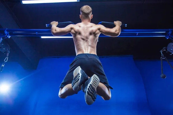 Hombre de fitness haciendo pull-ups en un gimnasio para una vista trasera de entrenamiento —  Fotos de Stock