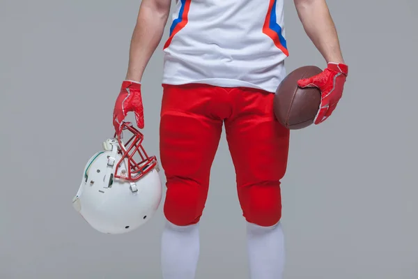 Primer plano del joven jugador de fútbol americano sosteniendo la pelota de rugby y el casco — Foto de Stock
