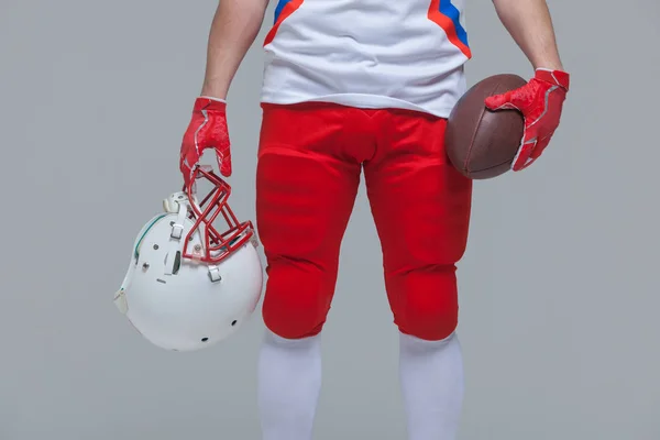 与手持橄榄球和头盔的年轻美国足球运动员亲密接触 — 图库照片