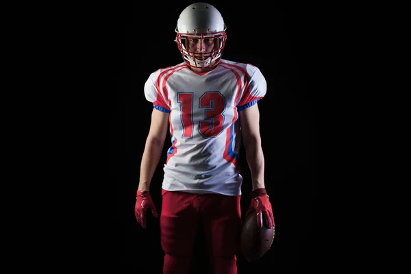 American Football-Spieler mit Helm posiert mit Ball auf schwarzem Hintergrund — Stockfoto