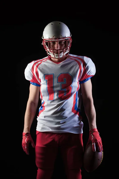 American Football-Spieler mit Helm posiert mit Ball auf schwarzem Hintergrund — Stockfoto