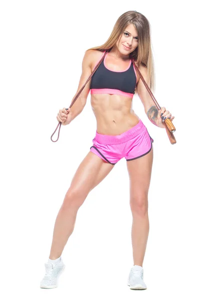 Chica atractiva, sexy y musculosa en pantalones cortos de color rosa y top negro sosteniendo una cuerda moderna con asas de madera. Fitness, concepto de estilo de vida saludable. Aislado sobre el fondo blanco . — Foto de Stock