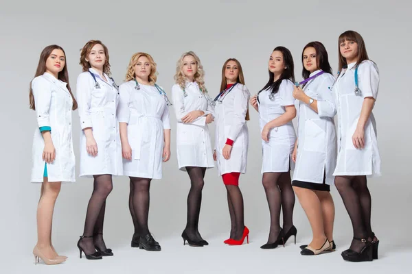 Full length portrait of a successful group of doctors staying in front of grey background — Stock Photo, Image