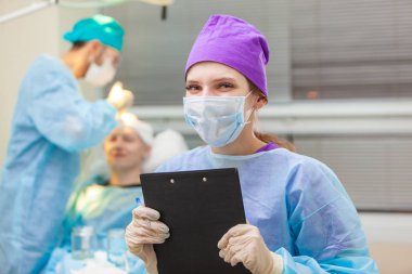 Ameliyathanenin arka planında belgeler olan bir doktorun güzel portresi. Kellik tedavisi. Saç ekimi. Ameliyathanedeki cerrahlar saç nakli ameliyatı gerçekleştirin. Cerrahi