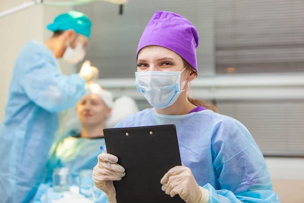 Beau portrait d'un médecin avec des documents sur le fond de la salle d'opération. Traitement de calvitie. Une greffe de cheveux. Les chirurgiens dans la salle d'opération effectuent une greffe de cheveux. Chirurgie — Photo