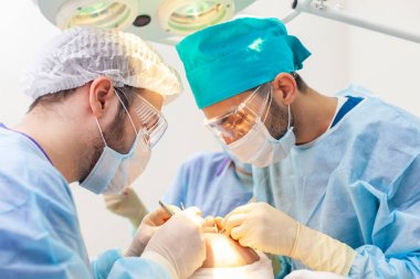 Kellik tedavisi. Saç ekimi. Ameliyathanedeki cerrahlar saç nakli ameliyatı gerçekleştirin. Saç köklerini başın bir kısmından hareket ettiren cerrahi teknik.