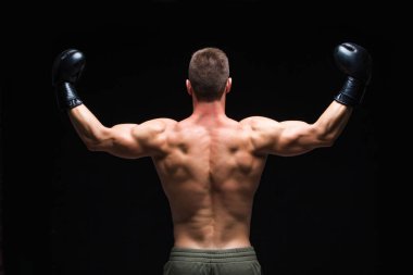 Güçlü sırt. Siyah boks eldiven ve şort Kaslı genç adam karanlık bir arka plan üzerinde stüdyoda farklı hareketleri ve grevgösterir. Güçlü Athletic Man - Fitness Modeli onun gösteren