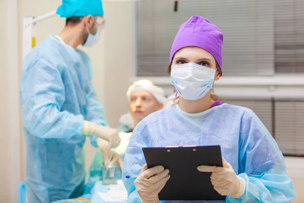 Beau portrait d'un médecin avec des documents sur le fond de la salle d'opération. Traitement de calvitie. Une greffe de cheveux. Les chirurgiens dans la salle d'opération effectuent une greffe de cheveux. Chirurgie — Photo