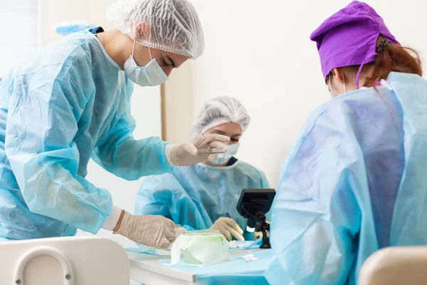 El médico al microscopio recalcula los folículos pilosos. Tratamiento de la calvicie. Trasplante de cabello. Los cirujanos en el quirófano llevan a cabo una cirugía de trasplante de cabello. Técnica quirúrgica que se mueve — Foto de Stock