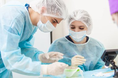 Mikroskop altındaki doktor saç köklerini yeniden hesaplar. Kellik tedavisi. Saç ekimi. Ameliyathanedeki cerrahlar saç nakli ameliyatı gerçekleştirin. Hareket eden cerrahi teknik