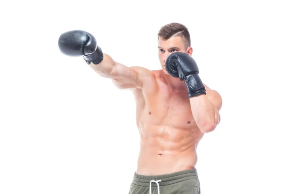 Gespierde jonge man in zwarte bokshandschoenen en shorts toont de verschillende bewegingen en stakingen in de studio op een witte achtergrond. Sterk atletisch man-fitness model dat zijn perfecte lichaam toont. Kopiëren — Stockfoto