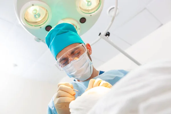 Retrato de um cirurgião no trabalho. Lâmpada no fundo. O cirurgião dá injeções na cabeça. Transplante capilar . — Fotografia de Stock