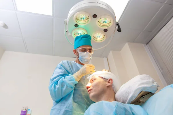 The surgeon gives injections to the head. Baldness treatment. Hair transplant. Surgeons in the operating room carry out hair transplant surgery. Surgical technique that moves hair follicles from a — Stock Photo, Image