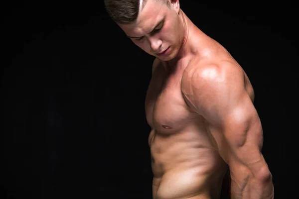 Stark atletisk man-fitness modell visar hans perfekt kropp isolerad på svart bakgrund med copyspace. Bodybuilder man med perfekt ABS, axlar, biceps, triceps och bröst. — Stockfoto
