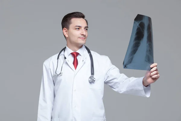 Fiatal férfi orvos nézi a röntgen képet a tüdő. — Stock Fotó