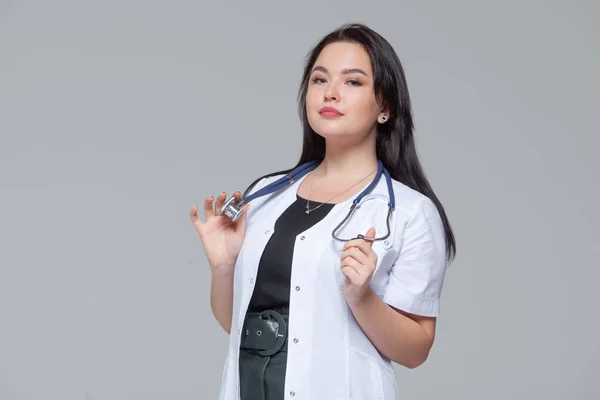 Портрет жінки-лікаря зі стетоскопом на сірому фоні — стокове фото