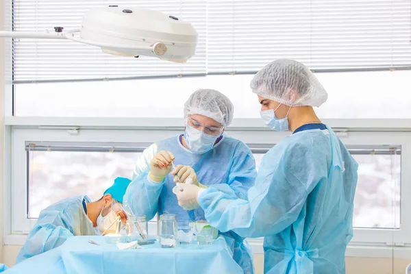 Tratamiento de la calvicie. Trasplante de cabello. Los cirujanos en el quirófano llevan a cabo una cirugía de trasplante de cabello. Técnica quirúrgica que mueve los folículos pilosos de una parte de la cabeza . — Foto de Stock