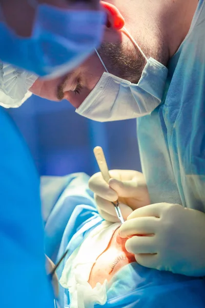 Surgeon and his assistant performing cosmetic surgery on nose in hospital operating room. Nose reshaping, augmentation. Rhinoplasty. — Stock Photo, Image