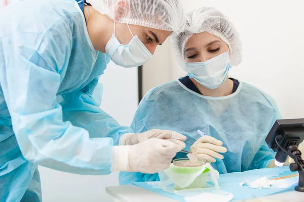 O médico sob o microscópio recalcula os folículos pilosos. Tratamento da calvície. Transplante de cabelo. Cirurgiões na sala de cirurgia realizar cirurgia de transplante de cabelo. Técnica cirúrgica que se move — Fotografia de Stock