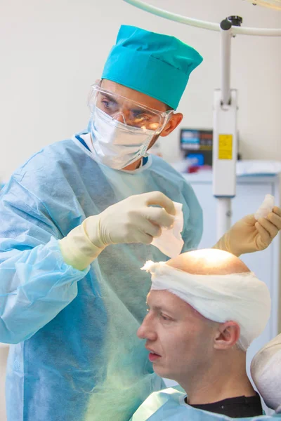 Ο χειρουργός δίνει ενέσεις στο κεφάλι. Θεραπεία της φαλάκρα. Μεταμόσχευση μαλλιών. Χειρούργοι στο χειρουργείο διεξάγουν εγχείρηση μεταμόσχευσης μαλλιών. Χειρουργική τεχνική που μετακινεί τα τριχοθυλακίων από ένα — Φωτογραφία Αρχείου