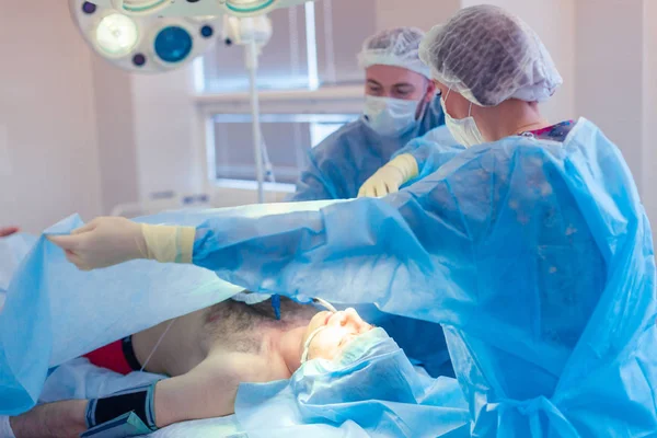 Equipe médica realizando operação cirúrgica na sala de cirurgia moderna — Fotografia de Stock