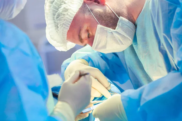 Cirujano y su asistente realizando cirugía estética en la nariz en el quirófano del hospital. Remodelación de la nariz, aumento. Rinoplastia . —  Fotos de Stock
