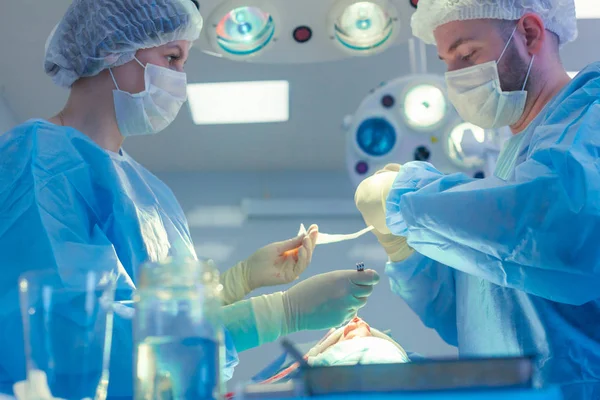 Medicinskt team som utför kirurgisk operation i moderna operationssalen. Näsplastik — Stockfoto