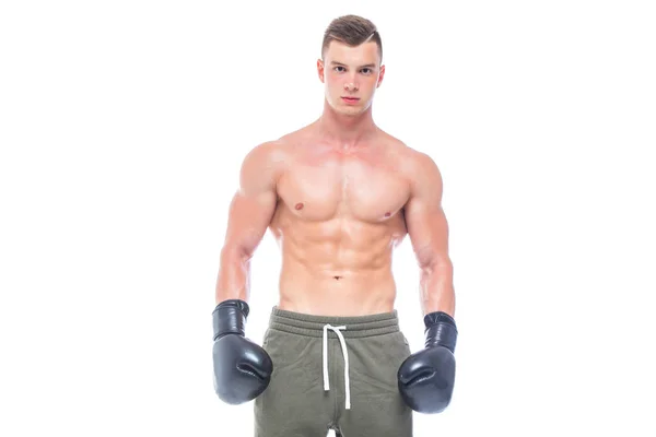 Gespierde jonge man in zwarte bokshandschoenen en shorts toont de verschillende bewegingen en stakingen in de studio op een witte achtergrond. Sterk atletisch man-fitness model dat zijn perfecte lichaam toont. Kopiëren — Stockfoto