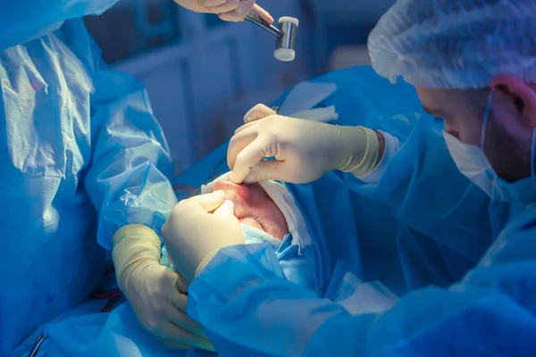 Хірург і його асистент виконують косметичну хірургію на носі в операційній кімнаті лікарні. Перетворення носа, розширення. Ринопластика. молотком . — стокове фото