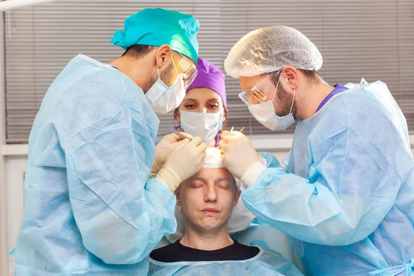 Tratamiento de la calvicie. Trasplante de cabello. Los cirujanos en el quirófano llevan a cabo una cirugía de trasplante de cabello. Técnica quirúrgica que mueve los folículos pilosos de una parte de la cabeza . — Foto de Stock