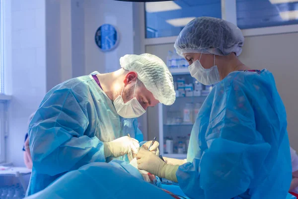 Medicinskt team som utför kirurgisk operation i moderna operationssalen. Näsplastik — Stockfoto