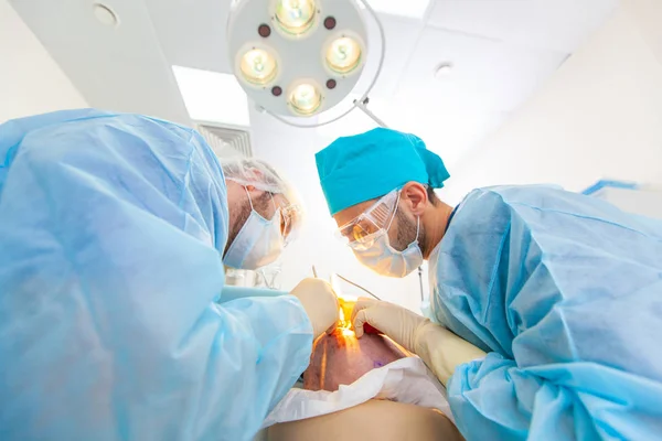 Baldness treatment. Hair transplant. Surgeons in the operating room carry out hair transplant surgery. Surgical technique that moves hair follicles from a part of the head.