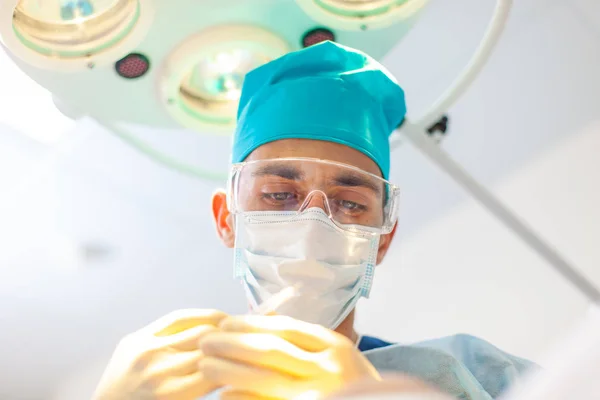 Beau portrait d'un chirurgien médecin au travail. La lampe en arrière-plan. Le chirurgien fait des injections à la tête. Traitement de calvitie. Une greffe de cheveux. Chirurgiens dans la salle d'opération effectuer des cheveux — Photo