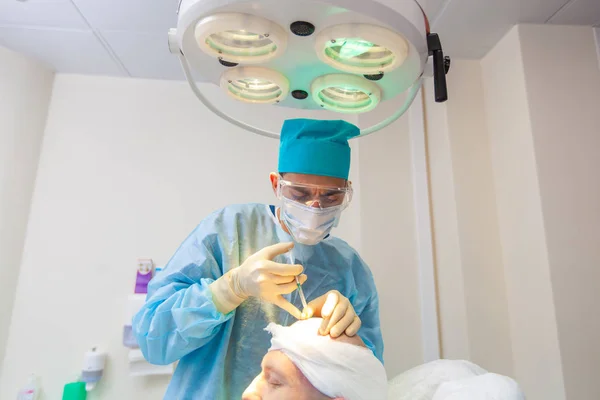 The surgeon gives injections to the head. Baldness treatment. Hair transplant. Surgeons in the operating room carry out hair transplant surgery. Surgical technique that moves hair follicles from a