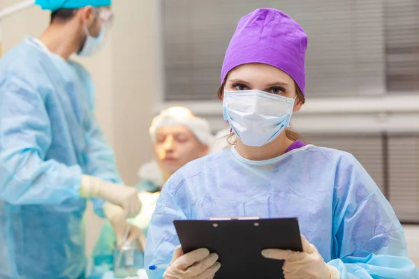 Beau portrait d'un médecin avec des documents sur le fond de la salle d'opération. Traitement de calvitie. Une greffe de cheveux. Les chirurgiens dans la salle d'opération effectuent une greffe de cheveux. Chirurgie — Photo