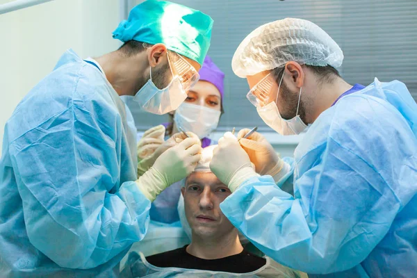 Tratamiento de la calvicie. Trasplante de cabello. Los cirujanos en el quirófano llevan a cabo una cirugía de trasplante de cabello. Técnica quirúrgica que mueve los folículos pilosos de una parte de la cabeza . — Foto de Stock