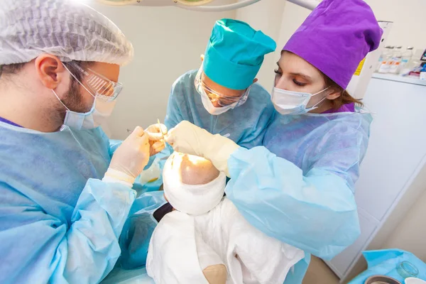 Baldness treatment. Hair transplant. Surgeons in the operating room carry out hair transplant surgery. Surgical technique that moves hair follicles from a part of the head. — Stock Photo, Image