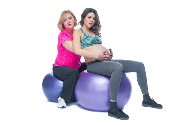 Young pregnant woman exercising with physiotherapist in birthing school. Doctors help conceptat in antenatal class. Isolated white background.